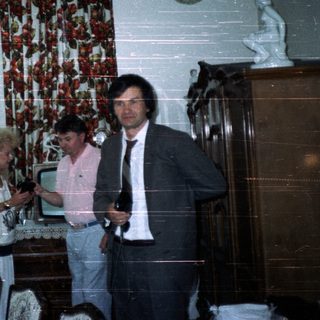 Three people in a dining room with a decorated table.
