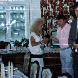 Three people in a dining room with a decorated table.