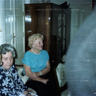 Three people seated in a room with a tall cabinet.