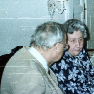Three people seated in a room with a tall cabinet.