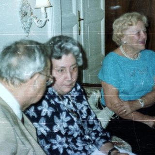 Three people seated in a room with a tall cabinet.