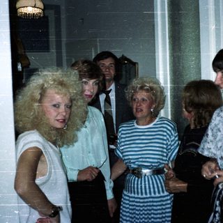 Group of people in 1980s attire posing indoors.