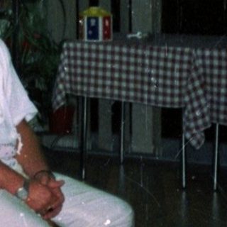 Here's a brief summary of the image: Three people sit as a woman provides medical treatment.