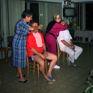 Here's a brief summary of the image: Three people sit as a woman provides medical treatment.