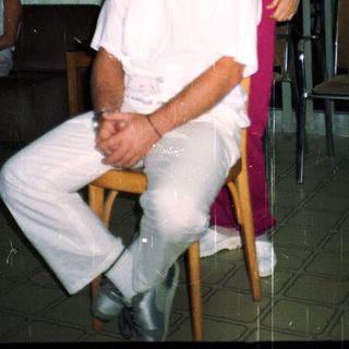 Man sits, woman stands behind him in a room.