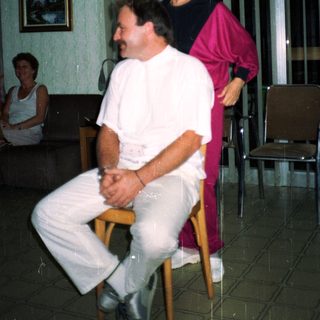 Man sits, woman stands behind him in a room.