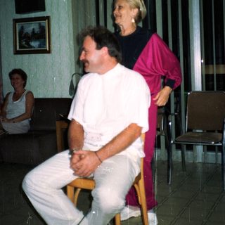 Man sits, woman stands behind him in a room.