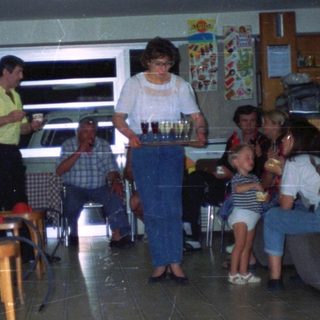 People gathered in a room, a woman serving drinks.