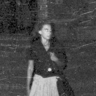 Here's a brief summary of the image: Two people stand near a building at night.