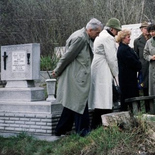Group gathers at a gravesite, possibly for a memorial.