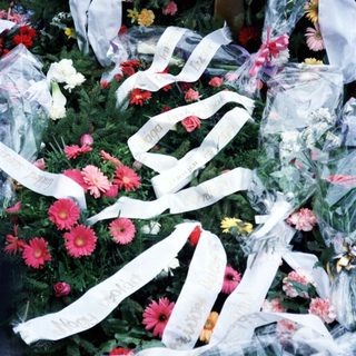 Floral tribute with ribbons, likely marking a memorial.