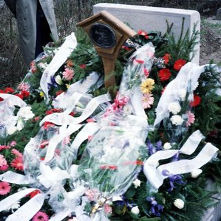 Here's a brief summary of the image: Flowers and ribbons adorn a grave or memorial.