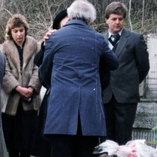 Group gathers near a memorial, possibly at a gravesite.