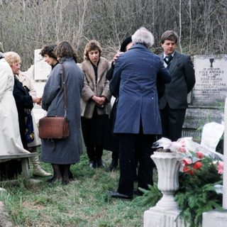 Group gathers near a memorial, possibly at a gravesite.