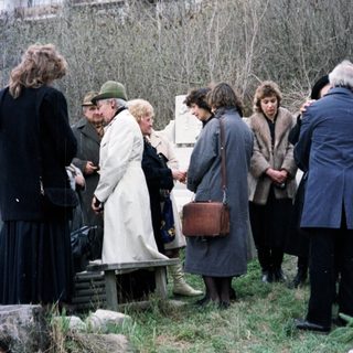 Group gathers near a memorial, possibly at a gravesite.