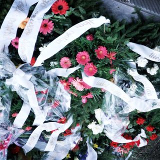Here's a brief summary of the image: Floral wreath with ribbons rests on a stone surface.
