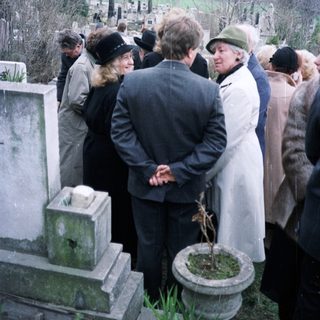 Group gathered at a graveside in a cemetery.