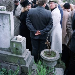 Group gathered at a graveside in a cemetery.