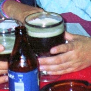 Two people sit at a table with drinks outdoors.