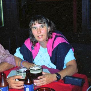 Two people sit at a table with drinks outdoors.