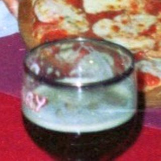 Two people sit at a table with pizza and drinks.