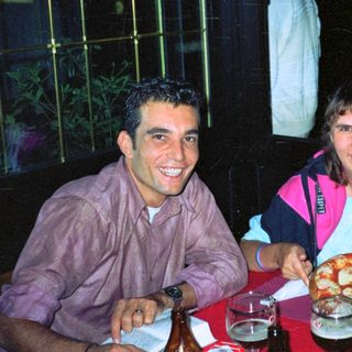 Two people sit at a table with pizza and drinks.