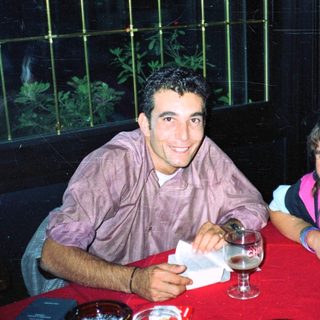 Here's a brief summary of the image: Two people sit at a table, smiling and relaxed.