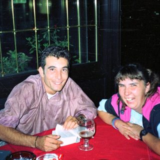 Here's a brief summary of the image: Two people sit at a table, smiling and relaxed.
