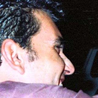 Two men appear to be playfully interacting in the dark.