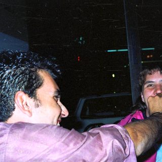 Two men appear to be playfully interacting in the dark.