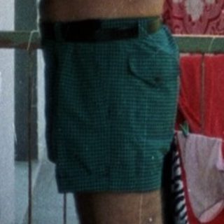 Man stands on balcony holding a drink, laundry drying.