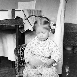 Here's a brief summary of the image: Young child seated on a chair, blurry motion.