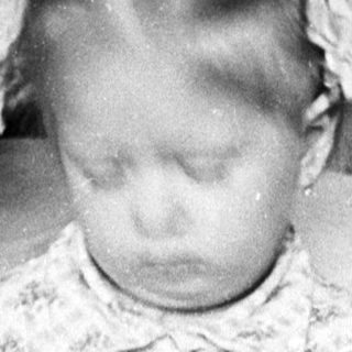 Here's a brief summary of the image: Young child seated on a chair, blurry motion.
