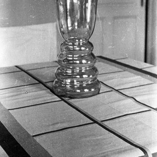 Black and white photo of a glass vase on a table.