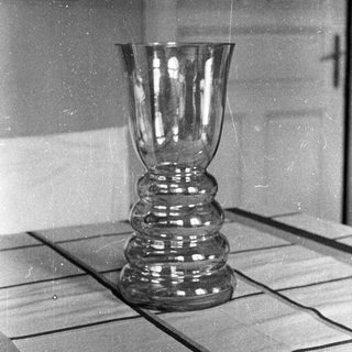 Black and white photo of a glass vase on a table.