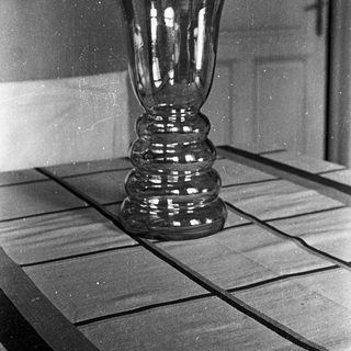 Black and white photo of a vase on a table.