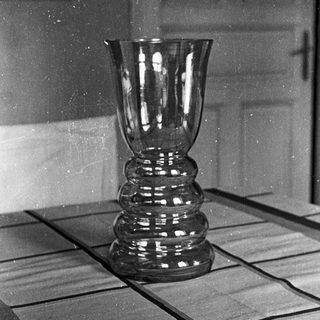 Black and white photo of a vase on a table.