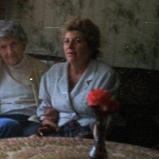 Three people sit on a couch in a lived-in room.