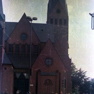 People stand near a church with a tall spire.