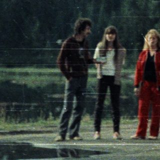 People standing near a forest with mountains in background.
