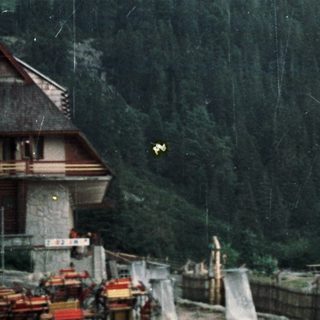 Mountain landscape with a building, terrace, and rain.