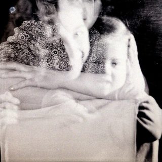 Here's a brief summary of the image: A woman and child, captured in a blurred, vintage photograph.