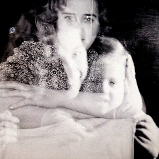 Here's a brief summary of the image: A woman and child, captured in a blurred, vintage photograph.