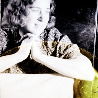 Here's a brief summary of the image: Woman with short hair sits at a table.
