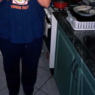 Person stands in a kitchen holding an item.