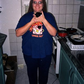 Person stands in a kitchen holding an item.