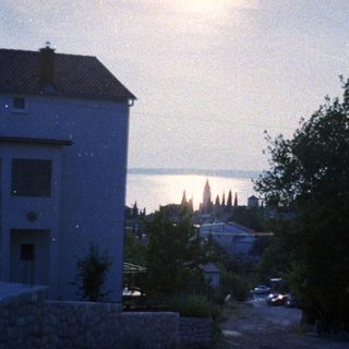 Coastal town at dusk, buildings, trees, and a view of water.