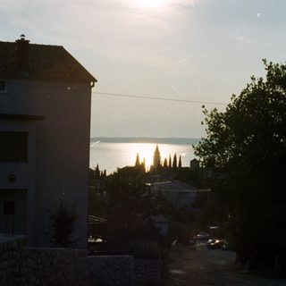 Coastal town at dusk with buildings and vegetation.