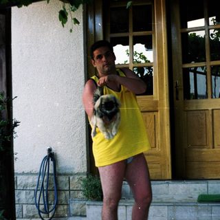 Man holding a dog outside a building.