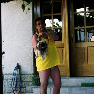 Man holding a dog outside a building.
